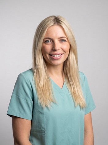 Dr Zara Collins, a dentist, wearing teal scrubs and smiling.
